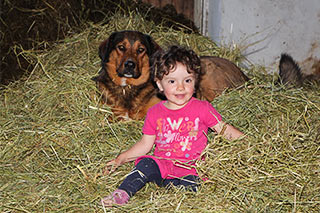 Sandra spielt im Heu mit Hofhund Lilli